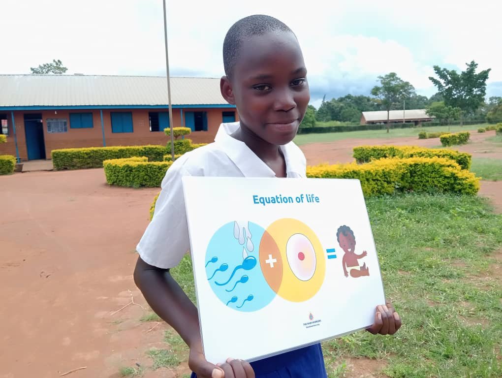 Eine Schülerin aus Uganda hat eines unsere Trainingsposter in der Hand, sie lernte in der Schule von unseren RAIN WORKERS, wie eine Frau schwanger werden kann